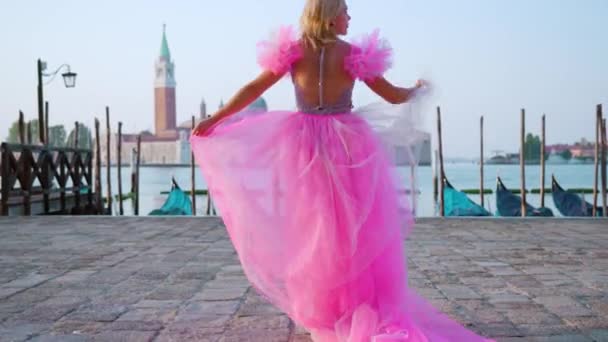 Mujer con hermoso vestido rosa camina delante de las góndolas en Venecia — Vídeo de stock