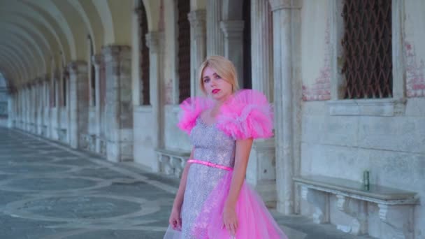 Menina com vestido rosa caminha sob as arcadas de Veneza — Vídeo de Stock
