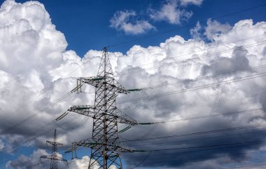 Güzel bulutların arka planında yüksek gerilimli tel direği.