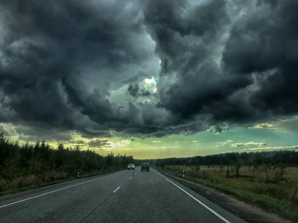 view from the car to the road with dark clouds.
