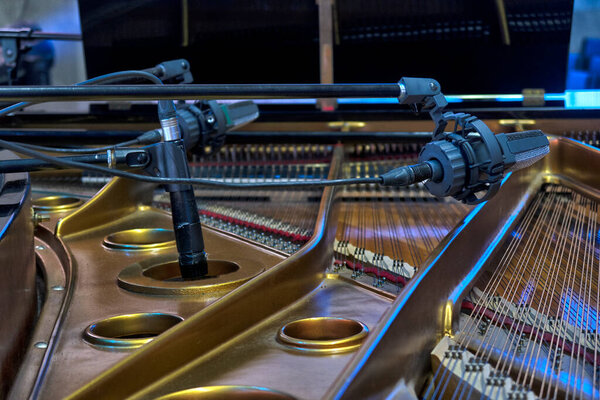 A black classic grand piano stands on stage . classical musical instrument close up