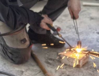 Metal meşale kullanarak çelik boru kesen işçiler