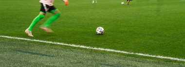 Futbolcunun ayakları zıplıyor ve topu doğal bir çimenlikte kontrol ediyor..