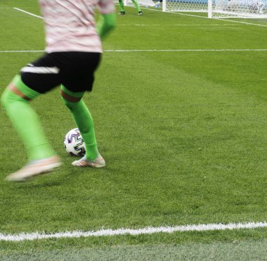 Futbolcunun ayakları zıplıyor ve topu doğal bir çimenlikte kontrol ediyor..