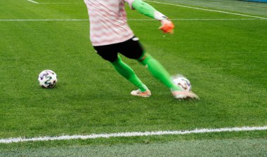 Futbolcunun ayakları zıplıyor ve topu doğal bir çimenlikte kontrol ediyor..