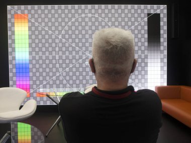 Televizyonun arka planında LED ekranı olan bir adam..