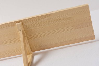 Duvara ahşap bir raf monte etme süreci, raf köşeleri bir kitaplık ile birlikte