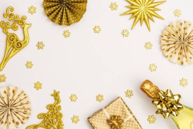 Altın madalyalı şenlikli arka plan, bir şişe köpüklü şarap, parlak altın yılanbalığı konfetisi ve kağıt Noel ağacı süslemeleri, ışıltılı kar taneleri ve Noel ağacı.