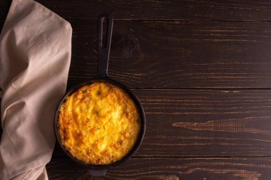 Peynirli frittata, mozzarella ve ahşap arka planda dökme demir bir tavada haşlanmış balkabağı.