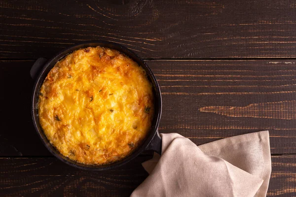 Peynirli frittata, mozzarella ve ahşap arka planda dökme demir bir tavada haşlanmış balkabağı.