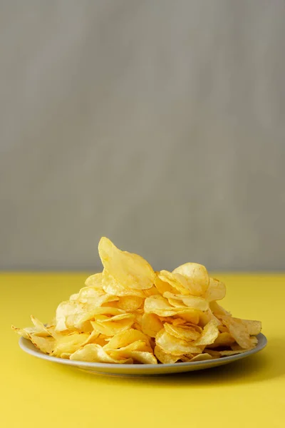 Knusprige Chips Auf Einem Grauen Teller Auf Einem Gelben Tisch — Stockfoto
