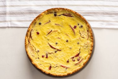 Elmalı ve yaban mersinli lezzetli peynirli turta, beyaz arka planda meyveli ve çilekli turta, mutfak havlusu, üst manzara