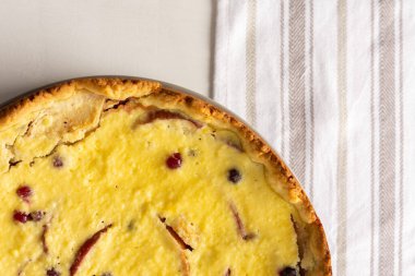 Elmalı ve yaban mersinli lezzetli peynirli turta, beyaz arka planda meyveli ve çilekli turta, mutfak havlusu, üst manzara