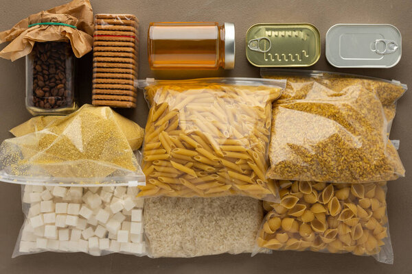 Продукты питания для дома, необходимые продукты питания на период карантина и изоляции, концепция пребывания дома, консервы, различные макаронные изделия и мука, сахар и печенье, вид сверху