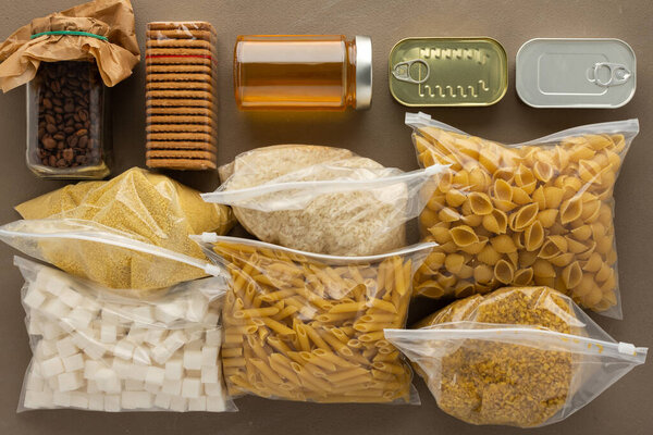 Продукты питания для дома, необходимые продукты питания на период карантина и изоляции, концепция пребывания дома, консервы, различные макаронные изделия и мука, сахар и печенье, вид сверху