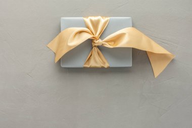 Gri arkaplanda altın fiyonklu gri hediye kutusu, doğum günü veya sevgililer günü konsepti, üst görünüm, kopyalama alanı