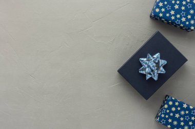 Mavi hediye kutusu ve mavi ambalajlı kutular. Yıldızlı güzel ambalajlar ve gri beton arka planda fiyonklar. Doğum günü ya da sevgililer günü konsepti.
