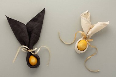 Gri arka planda peçeteden ve altın boyalı yumurtadan soyut paskalya tavşanları, Paskalya bayramı konsepti