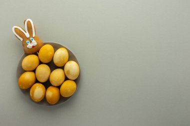 Paskalya sarısı boyalı yumurta ve bisküvi tavşanı gri arka planda, Paskalya bayramı konsepti yılın moda renkleri.