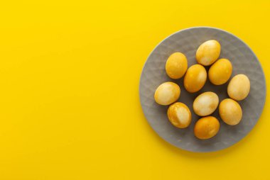 Sarı arka planda gri tabakta boyanmış Paskalya yumurtası, Paskalya bayramı konsepti