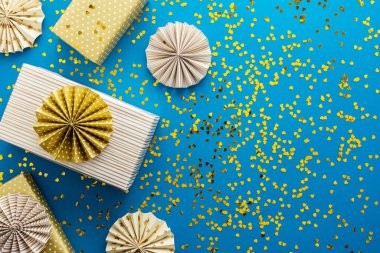 Altın hediye kutuları ve mavi arka planda altın kalpli kağıt Noel ağacı süslemeleri, doğum günü veya Noel konsepti