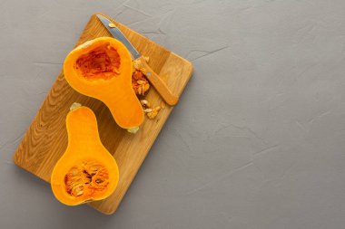 Çiğ organik tereyağlı balkabağı ya da ninem tahta tahtada yarı yarıya kesilmiş, arka planda gri beton bıçak, üst manzara, kopyalama bölmesi