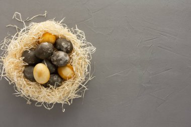 Saman yuvasında altın ve gümüş paskalya yumurtaları, gri beton arka planda izole edilmiş paskalya yuvası.