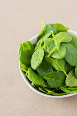 Sağlıklı sebze sebzeleri gri arka planda bir kasede, yeşil ıspanak yaprakları yakın, üst manzara