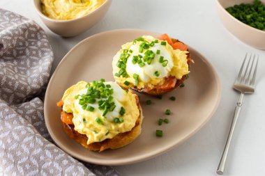 Lezzetli bir kahvaltı, beyaz bir zeminde Atlantik yumurtası, somon ve yumurtalı kızarmış çörek, Hollandaise sosu ve yeşil soğan.