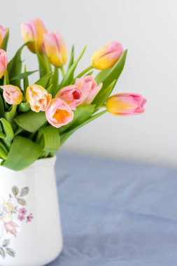 Masadaki sürahide pembe lale buketi, evin içinde çiçekler.