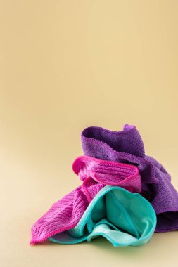 Tarafsız bir bej arka planda yıkanmak için çok renkli mikrofiber kumaşlar, temizlik konsepti.