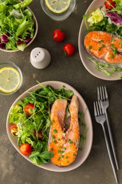 Lezzetli bir öğle yemeği, kızarmış alabalık bifteği ve değişik türde sebze salatası, sağlıklı kırmızı balıklarla akşam yemeği.