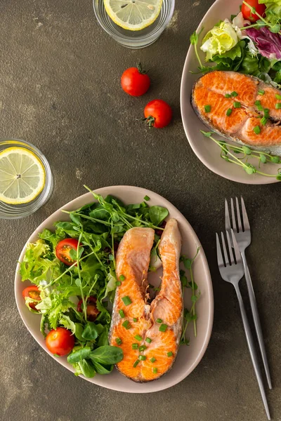 A delicious hearty lunch, a fried piece of trout steak and a mix of different types of greens salad, dinner with healthy red fish