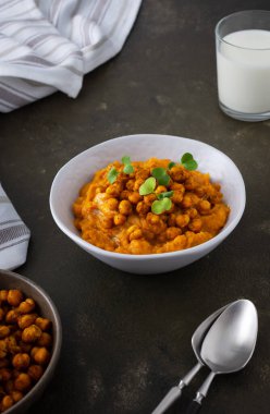 Kalın balkabağı çorbası, pişmiş nohut ve bir tabakta turp lahanası, masada bir bardak süt, lezzetli sağlıklı bir akşam yemeği.