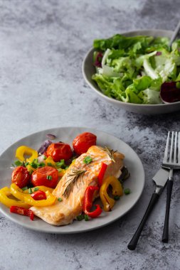 Pişmiş kırmızı balık fileto. Sebzeli bir tabakta Arktik char. Salatayı bir kasede karıştır.