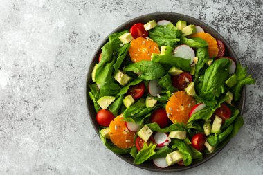 Ispanak yaprakları, mandalina ve avokado dilimleri, çekirdekli domates ve turp, yakın plan salata, üst görünüm, kopyalama alanı