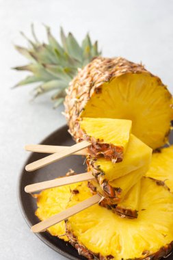 Olgun sulu ananas, yakın plan halkalara kesilmiş, ananas şeklinde bir çubuk üzerinde dondurma.