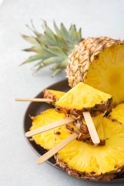 Olgun sulu ananas, yakın plan halkalara kesilmiş, ananas şeklinde bir çubuk üzerinde dondurma.
