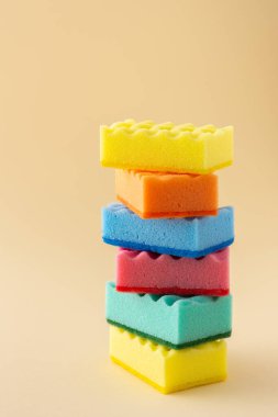 Tarafsız bej arka planda çok renkli bulaşık süngeri yığını, mutfak ve temizlik konsepti