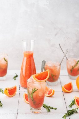 Biberiyeli soğuk, ferahlatıcı greyfurt püresi ve bardakta buz, greyfurt dilimleri ve masada biberiye filizi, ev partisi.