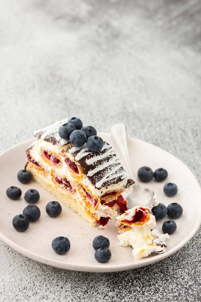 Çikolata serpiştirilmiş ısırılmış bir parça kek ve üzerine de yaban mersini serpiştirilmiş hindistan cevizi.