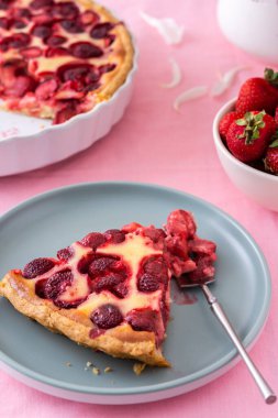 Pembe masa örtülü bir masa, bir buket şakayık ve tatlı çilekli turta, tabakta bir dilim turta, lezzetli bir yaz tatlısı.