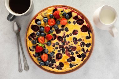 Gri arka planda taze böğürtlenlerle süslenmiş çilekli turta.