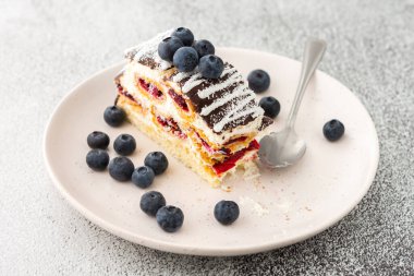 Çikolata serpiştirilmiş ısırılmış bir parça kek ve üzerine de yaban mersini serpiştirilmiş hindistan cevizi.