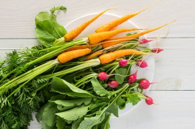 Taze toplanmış taze turplar ve yeşil uçlu havuçlar beyaz ahşap arka planda, sebze bahçesinden organik ürünler.