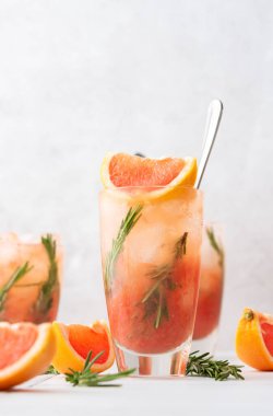 Biberiyeli soğuk, ferahlatıcı greyfurtlu smoothie yakın plan, greyfurt dilimleri ve masada biberiye filizi, ev partisi