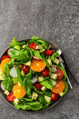 Ispanak yaprağı, mandalina ve avokado dilimleri, çekirdekli domates ve turp, çatallı bir tabakta salata, üst manzara, kopyalama alanı.