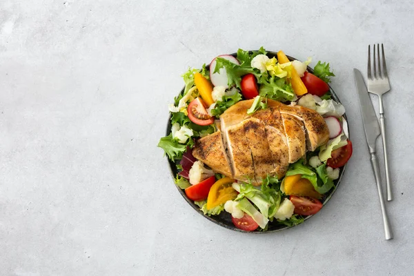 Lezzetli bir öğle yemeği, baharatlı tavuk göğsü ve domatesli salata, turp ve karnabahar karışımı.