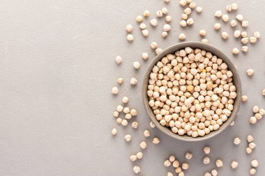 Baklagiller kasede ve arka planda dağınık, gri arka planda bir tabakta nohut, üst manzara, kopyalama alanı