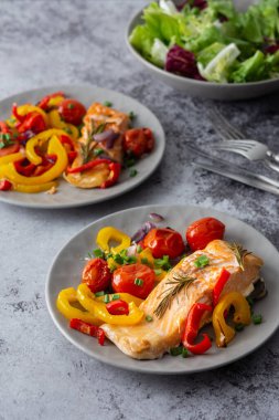 Pişmiş kırmızı balık fileto. Sebzeli bir tabakta Arktik char. Salatayı bir kasede karıştır.